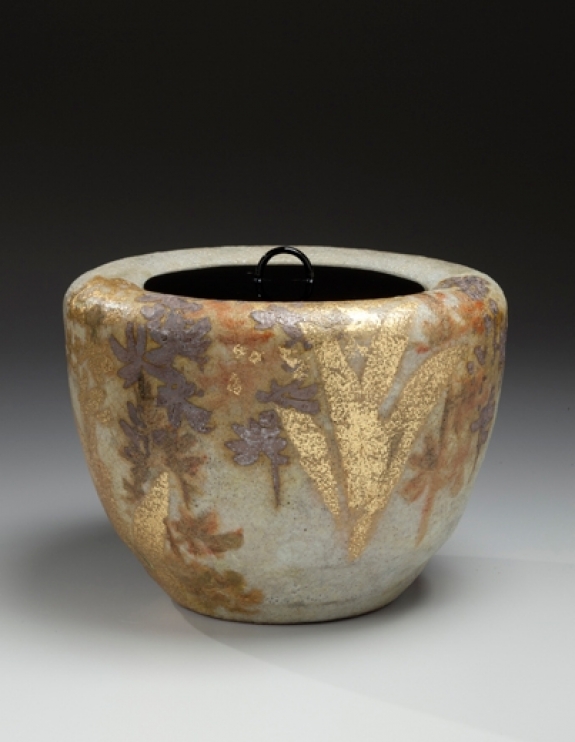 Kiyomizu Rokubei VI (1901-1980). Mizusashi (water jar) with floral patterning of an ebine (calanthe orchid) and lacquer lid. Japan, circa 1978. Kokisai-glazed stoneware with gold and silver. 6.38 x 8.5 inches (16.2 x 21.6 cm). 