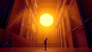 Olaf Eliasson stands in a gallery at the Tate Modern beneath his light sculpture, The Weather Project (2003-2004).