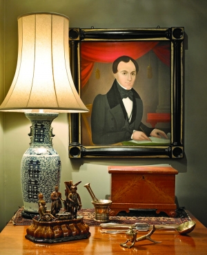 The crisp and spare anonymous portrait of an unidentified man is painted on wood and is in its original frame. On the table is one of the rarest pieces of American yellow ware with a Rockingham glaze. This figural inkwell, on an inverted vegetable dish, made at the Harker and Taylor pottery (active 1851–1871) in Liverpool, Ohio, is referred to in the company’s records as “William Penn Treating with the Iroquois.” Two other examples are pictured in Harker Pottery from Rockingham and Yellowware to Modern, by William and Donna Gray (Schiffer, 2006).